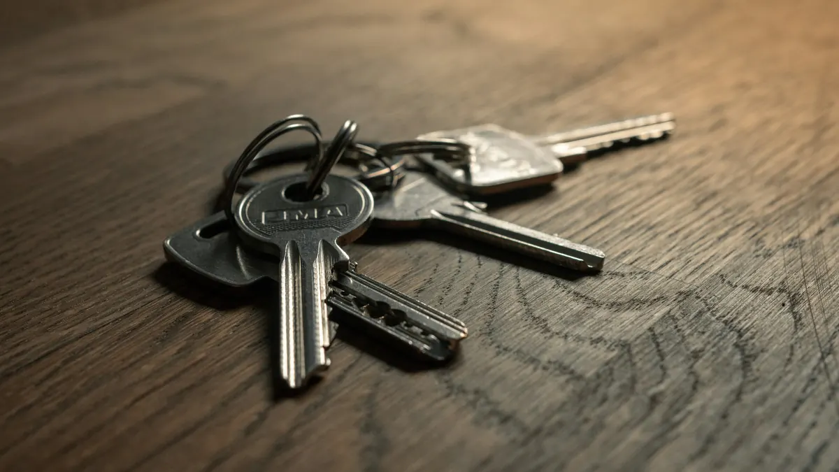 A bunch of metal house keys on a ring lying on a dark wooden table